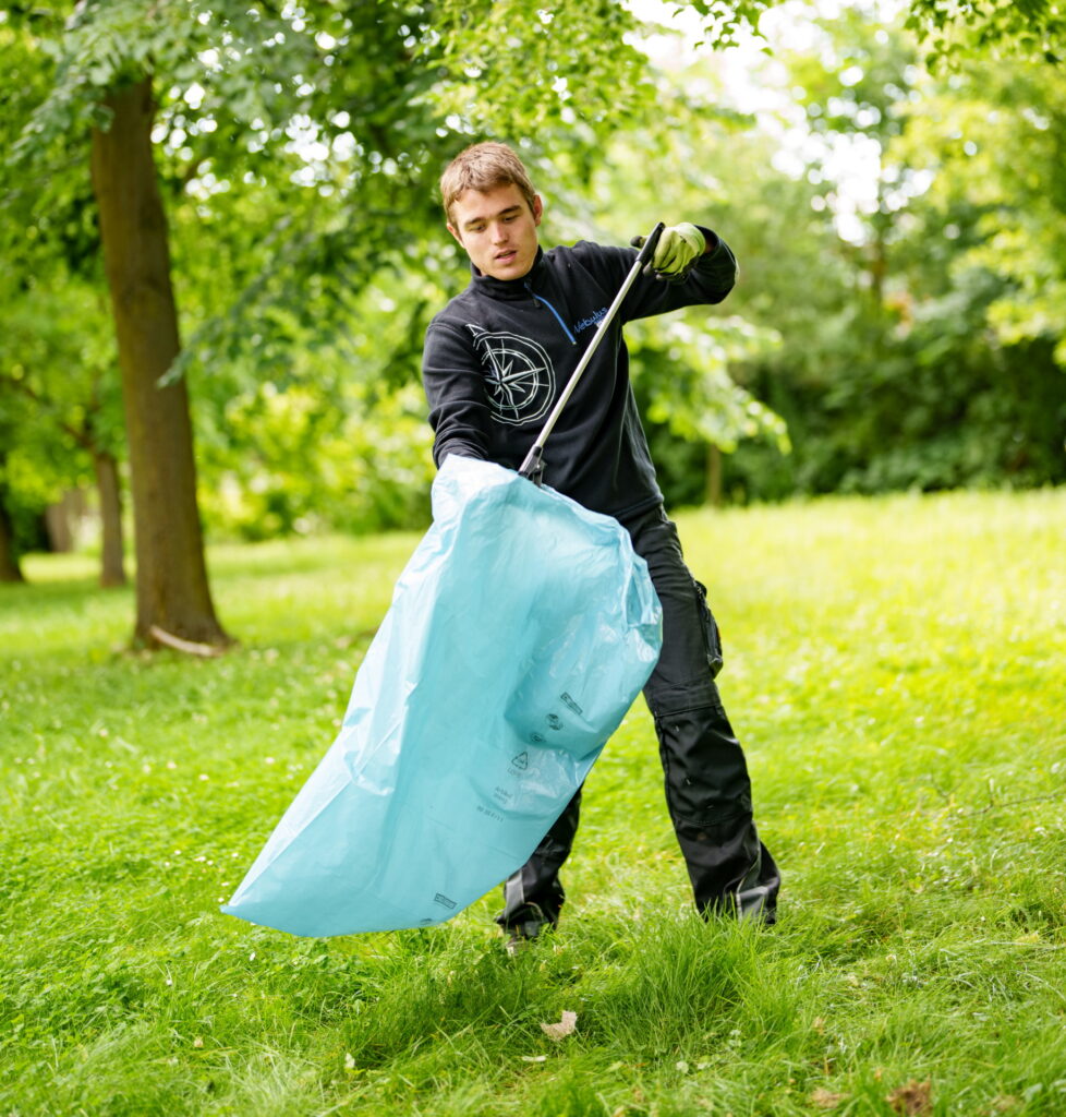 Lukas Szardin beim Müllaufsammeln mit Müllsack und Zange