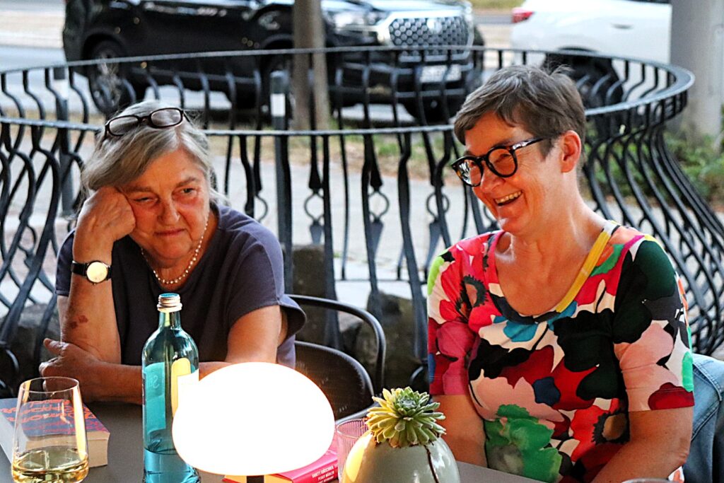 Zwei Frauen sitzen nebeneinander an einem Tisch.